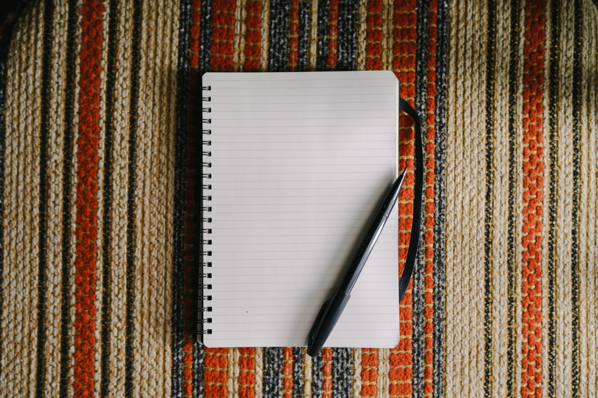 A blank notebook with a pen on a desk, ready for essay writing