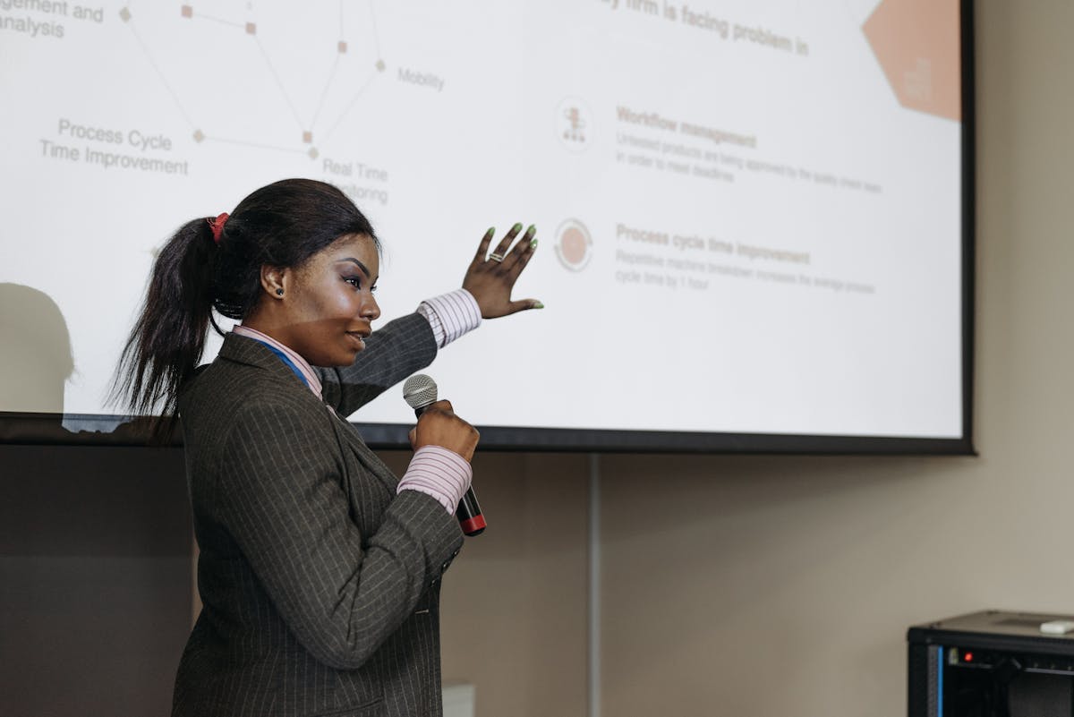 A businesswoman presenting with a microphone in front of conference slides